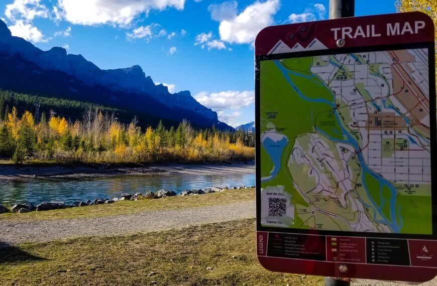 a sign of the trail route in front of the mountains