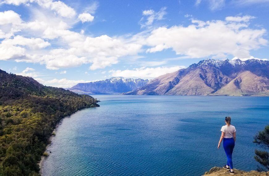 standing at the edge of lake wakatipu in new zealand