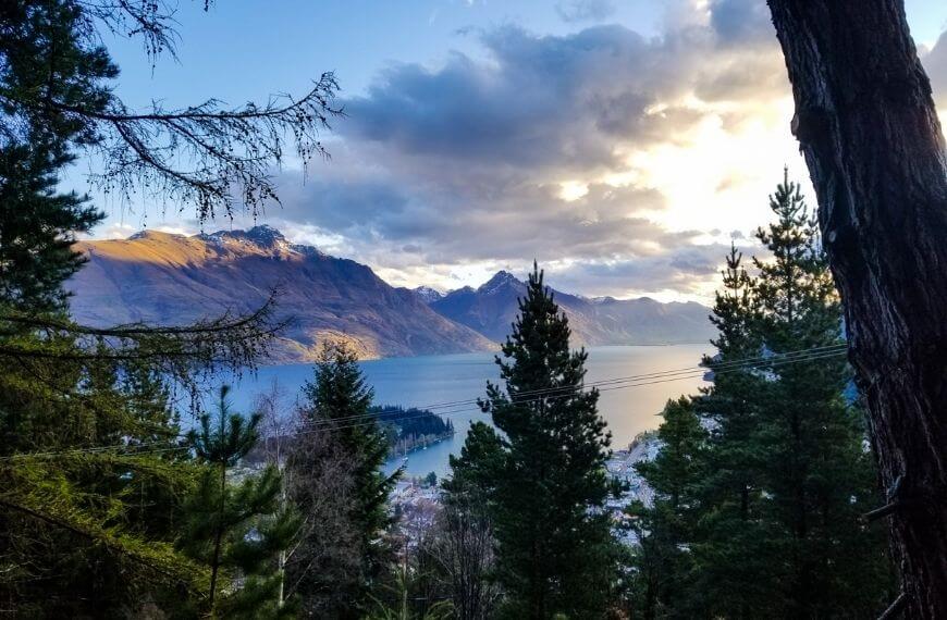 view of the mountains and lake through the trees on the trail
