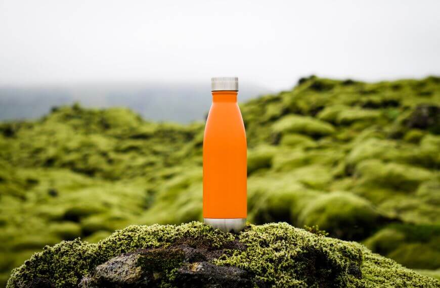 orange water bottle on a mossy rock