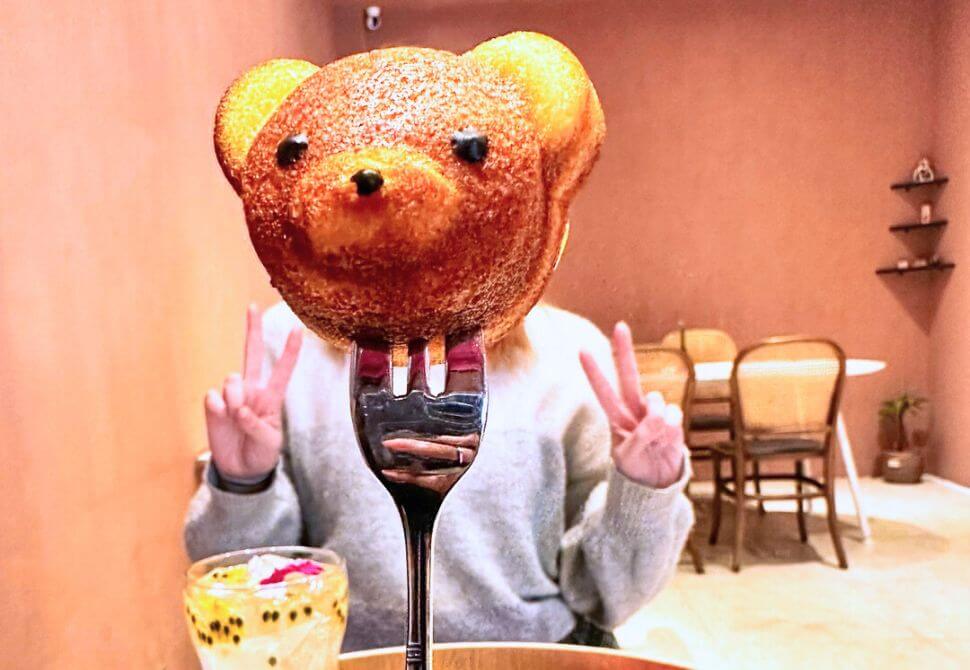 teddy bear shaped cake on a fork in front of someones face at one of the popular themed cafes in Busan