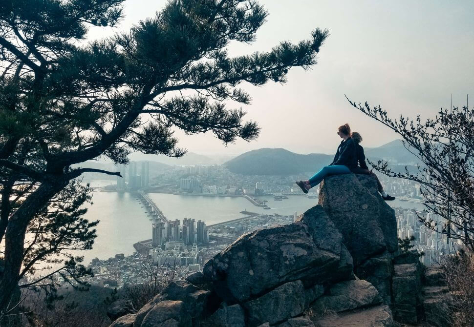 My friend and I sitting on a rock at the peak of Bongnaesan mountain overlooking Busan port - one of the best hikes in the city