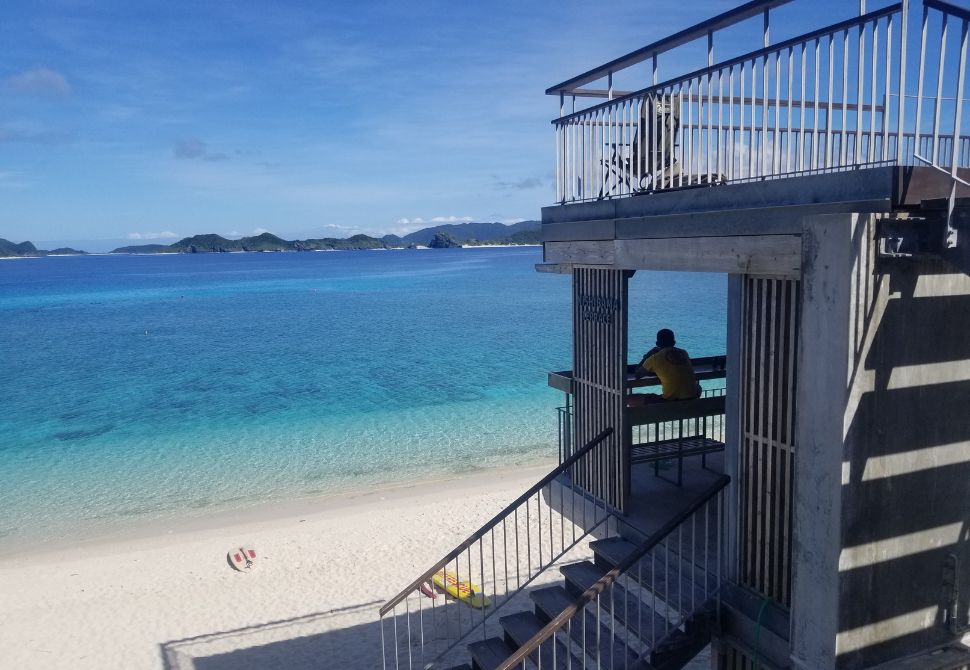 The concrete and wooden terrace above Aka Island's most famous beach with white sand and bright blue water 